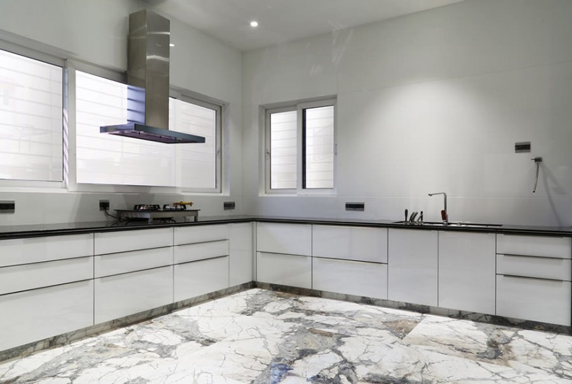 L-Shaped White Kitchen Consists of Black Granite Counter Top with Gas Stove, Chimney & Built-In Sink