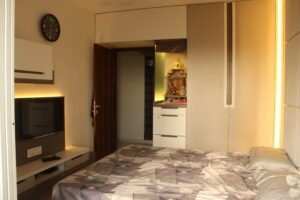 The Bedroom consists of Rectangular Wooden Bed & Wall Mounted T.V. Unit