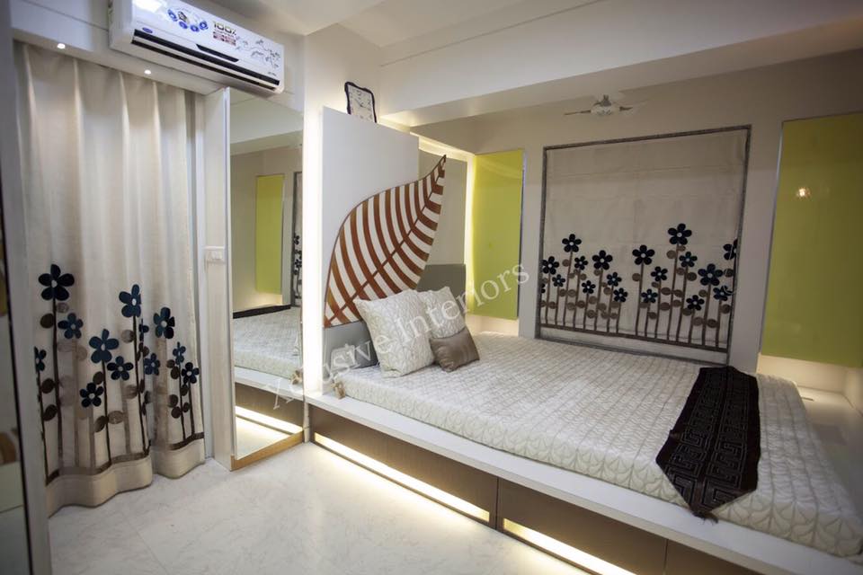 A Single Rectangular Wooden Bed having cushioned backrest is nicely placed on one side of the Bedroom