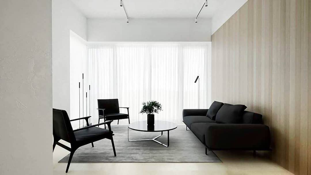 The Black Upholstered 2 Seater Sofa having Metal Legs is Nicely Placed in the White Bedroom